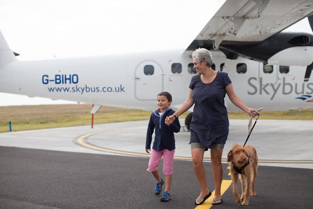 woman with a child and dog disembarking from a  Skybus aircraft