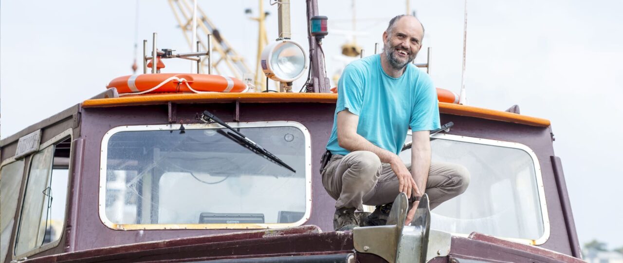 John Peacock crouched down on the front of his boat