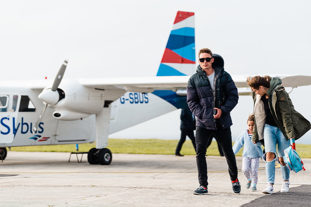 Family arriving at St Mary's Airport on a Skybus Islander aircraft