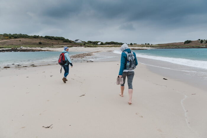 people walking across the bar on St Agnes in the rain