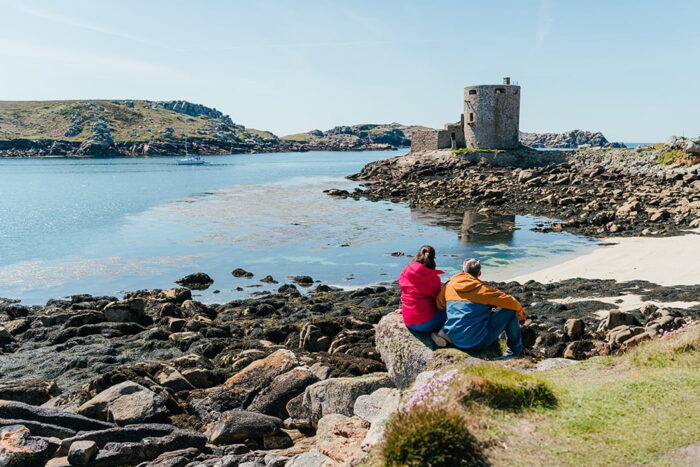 Couple sitting in front of Cromwell castle, Tresco, Isles of Scilly