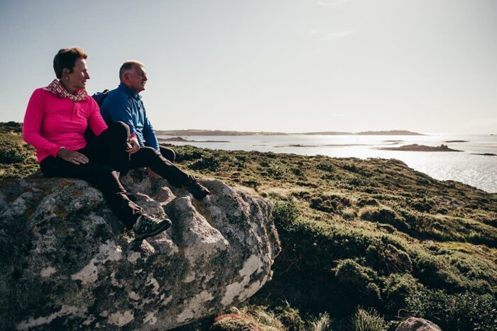Couple looking across to Samson from Bryher, Isles of Scilly in autumn.