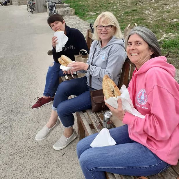 Friends eating pasties by Porthcressa beach, St Mary's, Isles of Scilly
