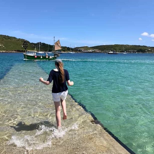 woman paddling her feet while waiting for the ferry from Bryher.