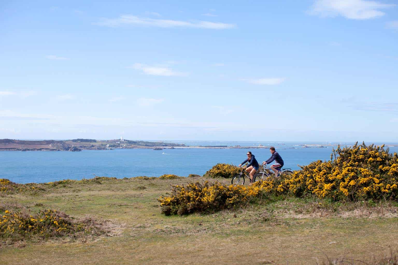Couple cycling along coastal paths on St Mary's, Isles of Scilly