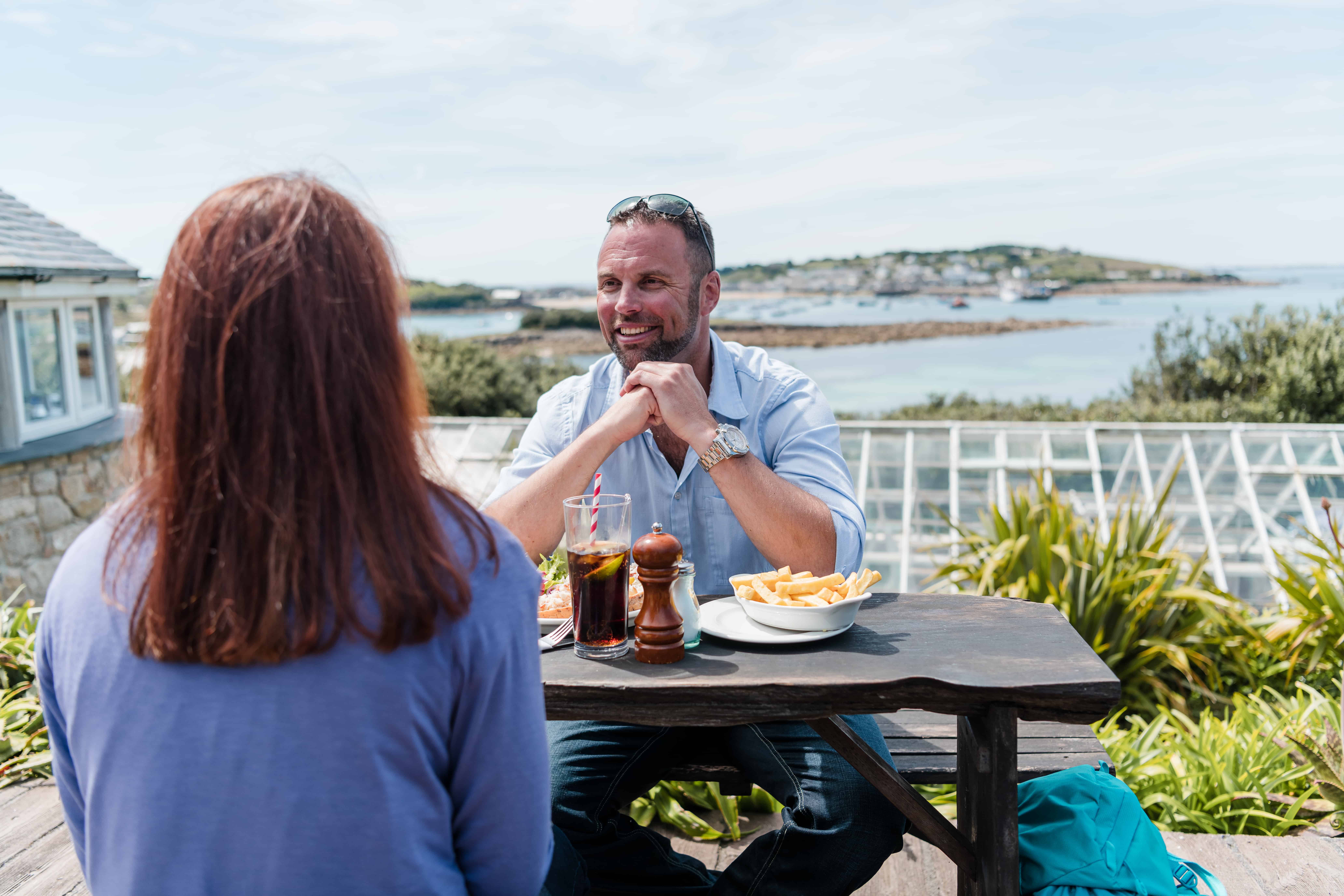 Couple enjoying alfresco dining in a restaurant with harbour views on St Mary's, Isles of Scilly