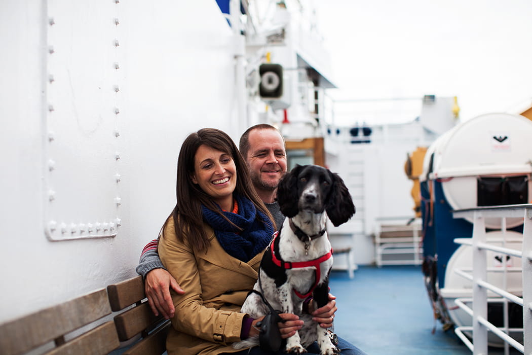 Couple with their dog, sitting outside on Scillonian III passenger ferry