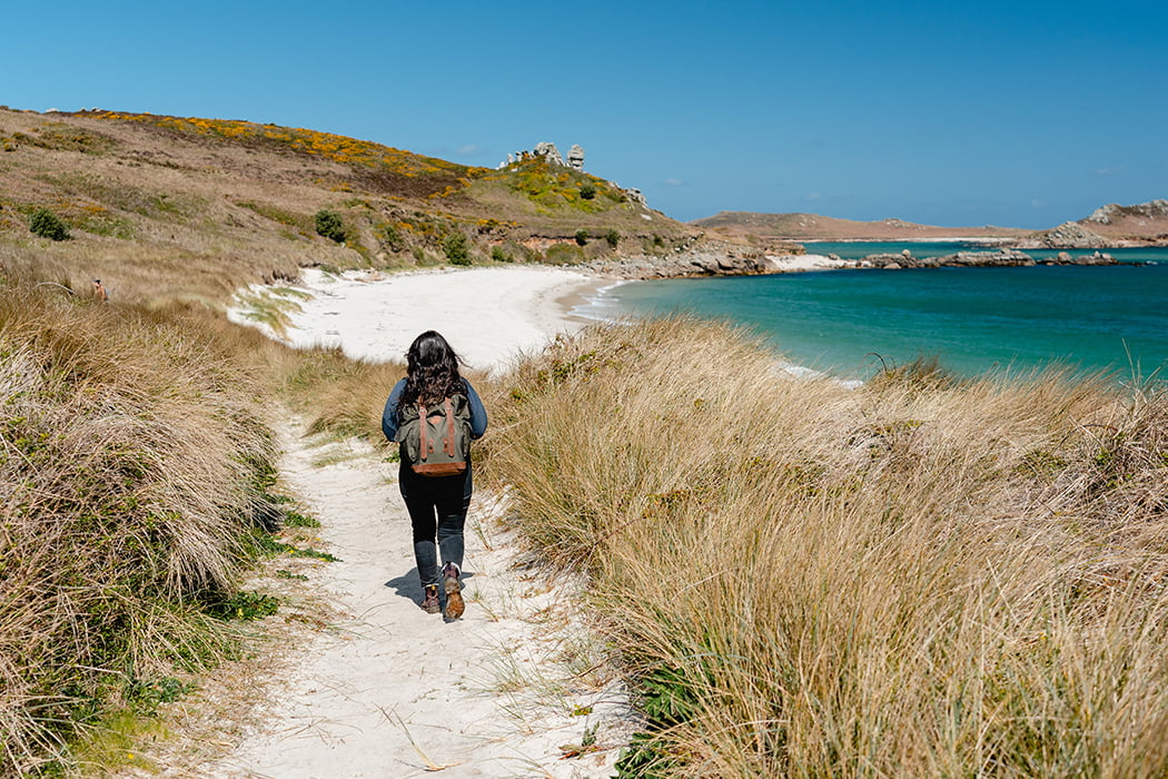 woman walking to little bay beach, St Martin's, Isles of Scilly in spring