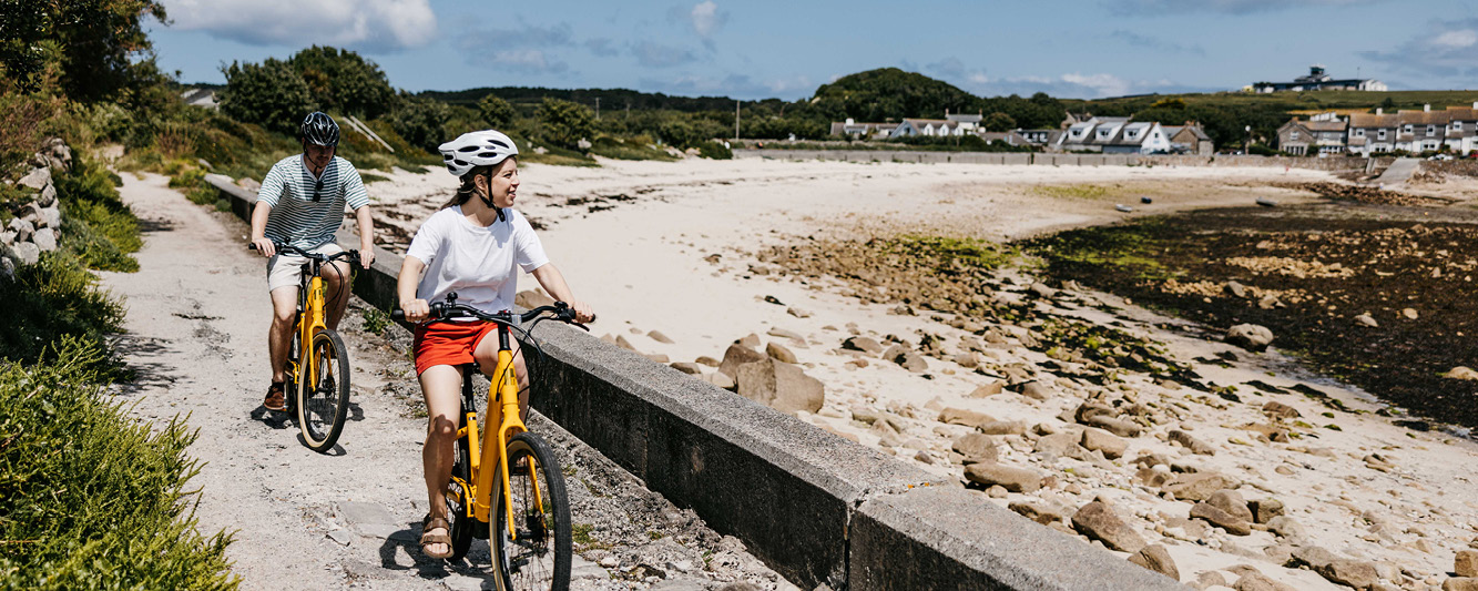 A couple cycling beside a beach