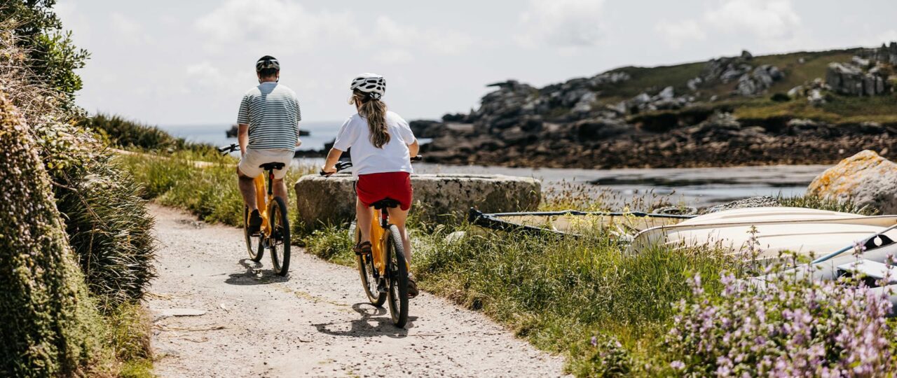 Couple cycling on bikes - Old Town, St Mary's, Isles of Scilly