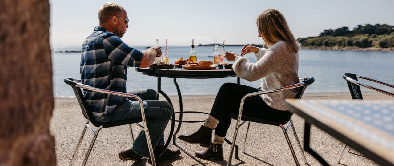 Couple enjoying lunch outside, Porthcressa Beach, St Mary's, Isles of Scilly