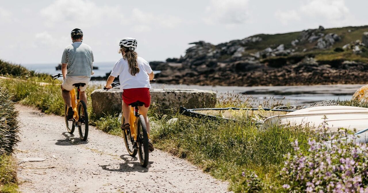 Couple cycling on bikes - Old Town, St Mary's, Isles of Scilly
