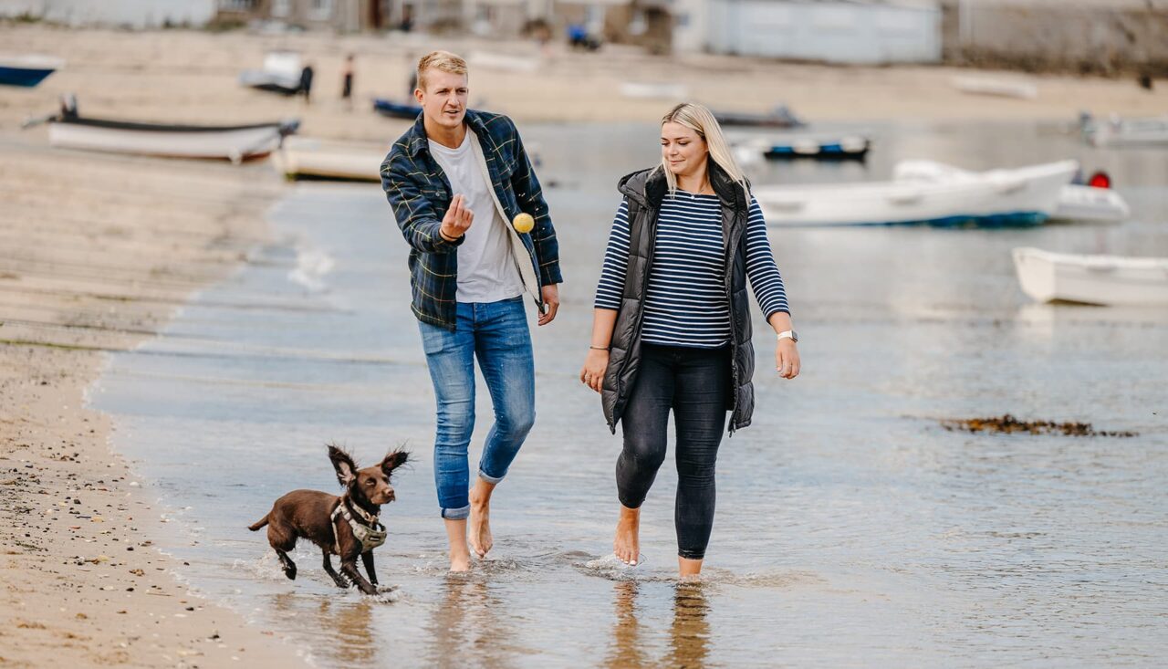 Couple playing ball with their dog along Town Beach, St Mary's - Isles of Scilly