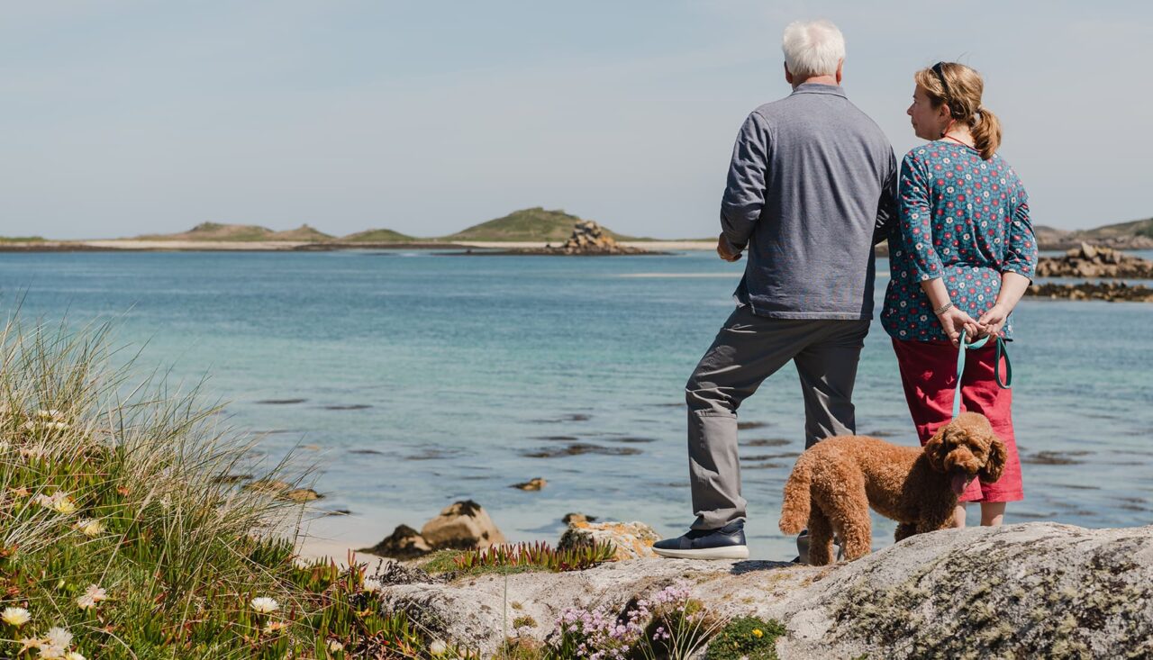 Couple walking with their dog along Pentle Bay, Tresco, Isles of Scilly