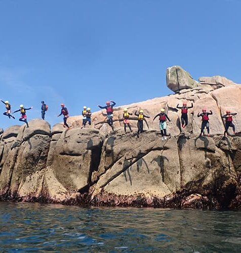 a group of people on a coasteering tour jumping from Peninnis head, St Marys