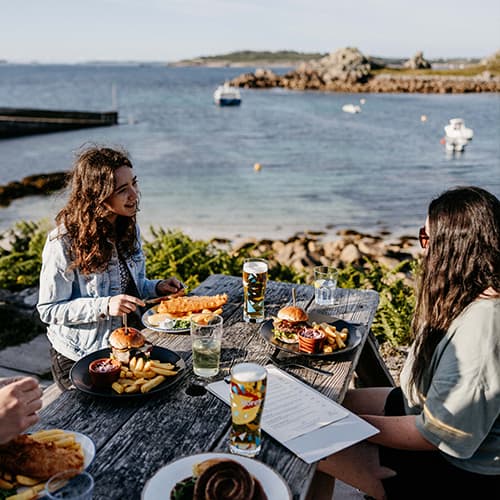 friends eating outside The Turks Head pub, St Agnes. Isles of Scilly