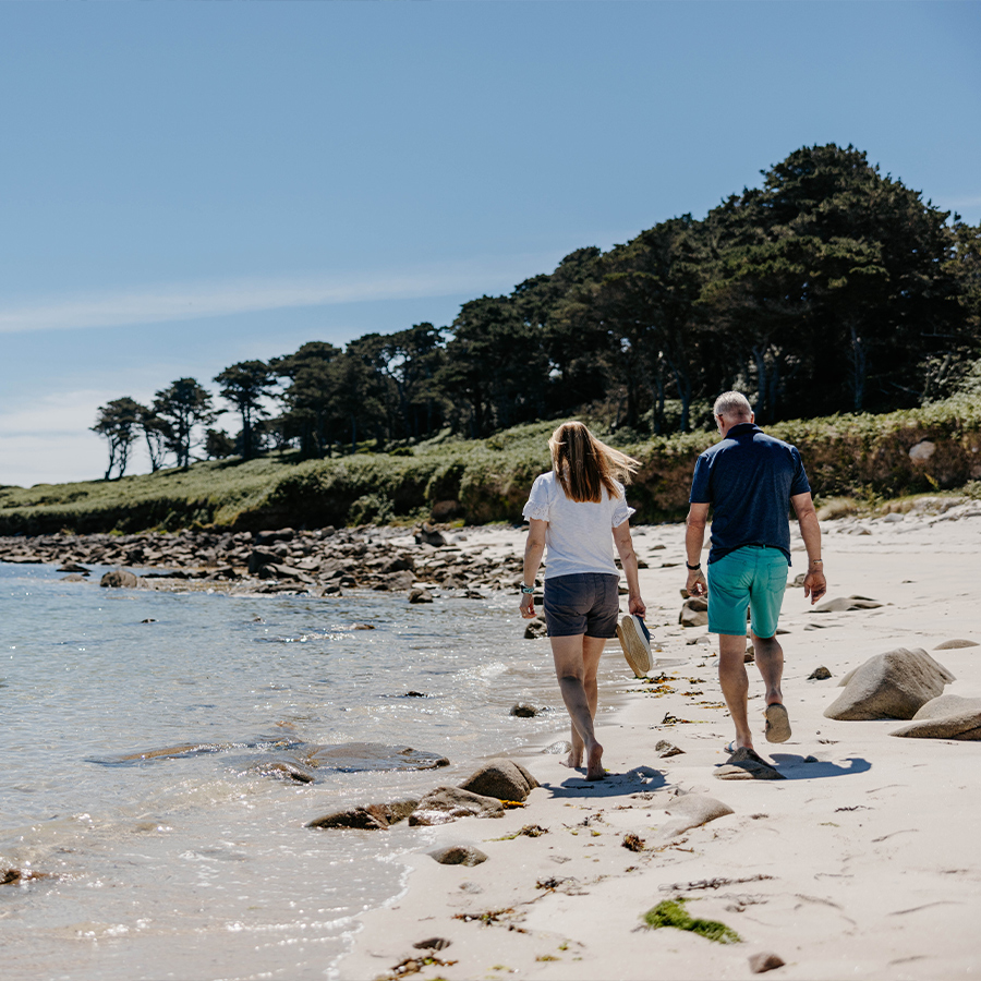 Couple walking along bar point beach, St Mary's in the summer