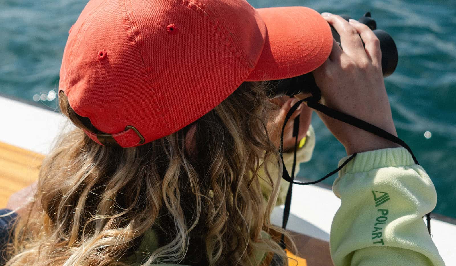 Lydia Cooke using binoculars on a wildlife and sightseeing boat trip, Isles of Scilly