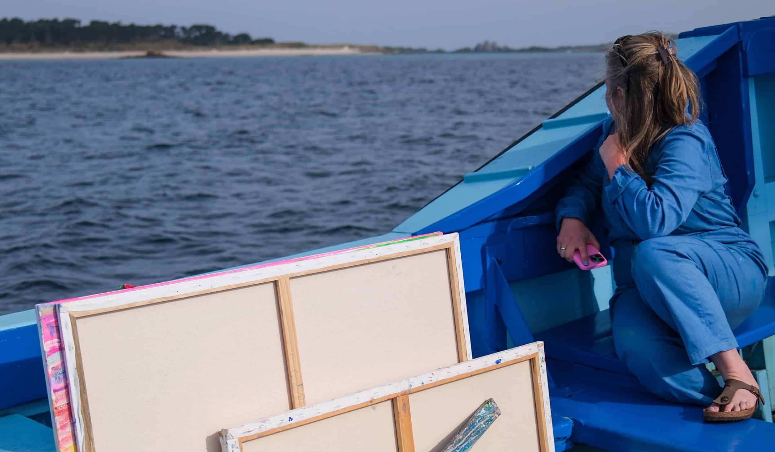 Artist Emily Powell on a tripper boat with her canvases, Isles of Scilly