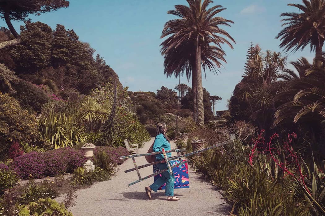 Emily Powell walking with easel and artwork, Tresco Abbey Garden