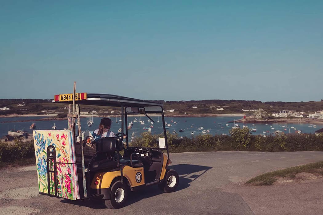 Emily Powell driving a Scilly Cart with her artwork on the back