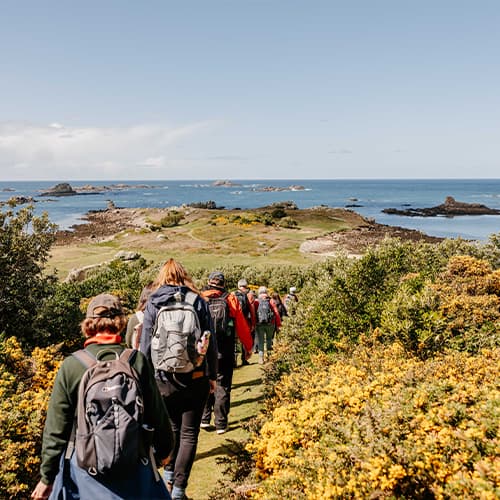 Walking group touring the coastal path around Bryher, Isles of Scilly