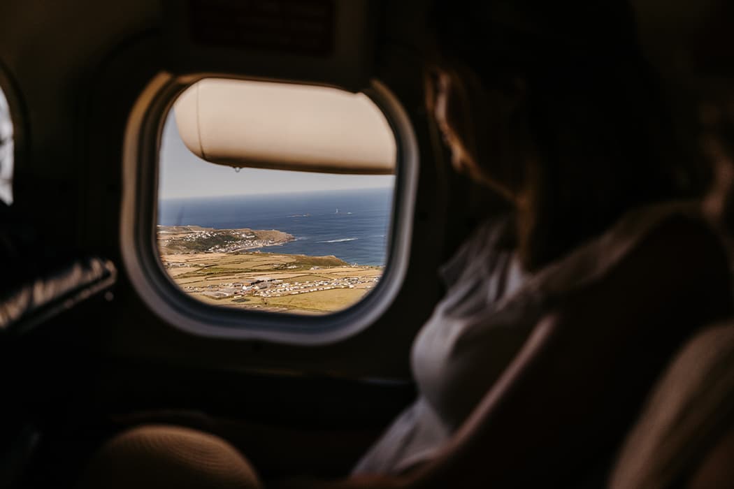 passenger looking out the window of a Skybus aircraft with a view of the Isles of Scilly