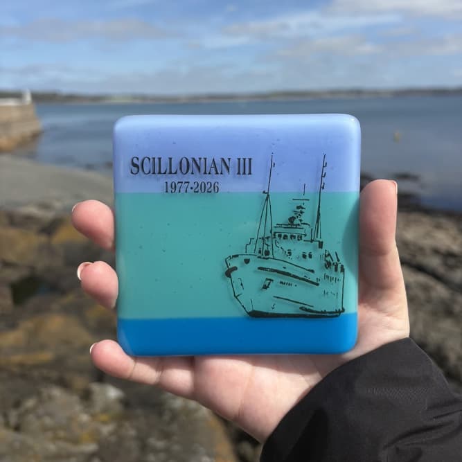Oriel Hicks stained glass coaster being held in front of the sea.