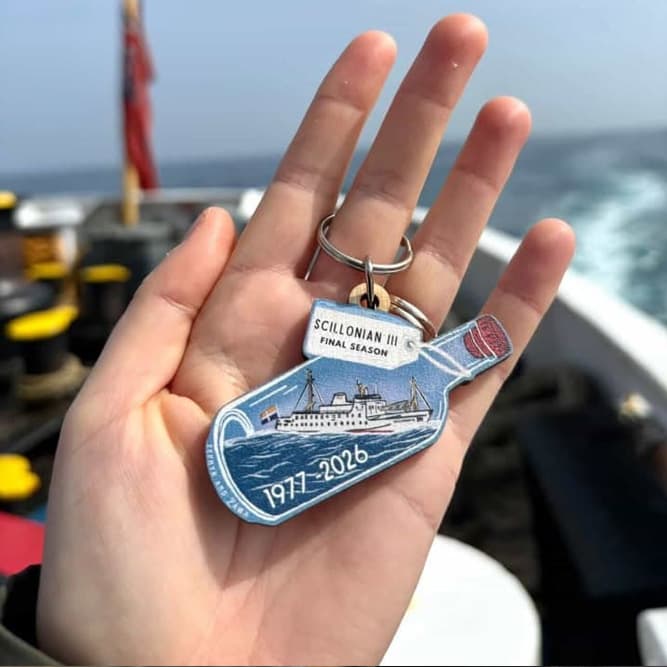 Zephyr and Zawn Scillonian III keyring being held on board the ship with the sea in the background.