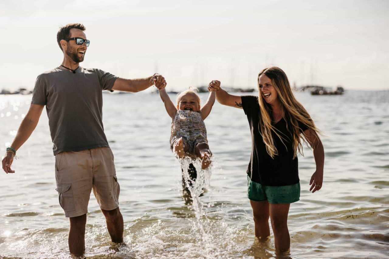Family playing on the beach along the shore.