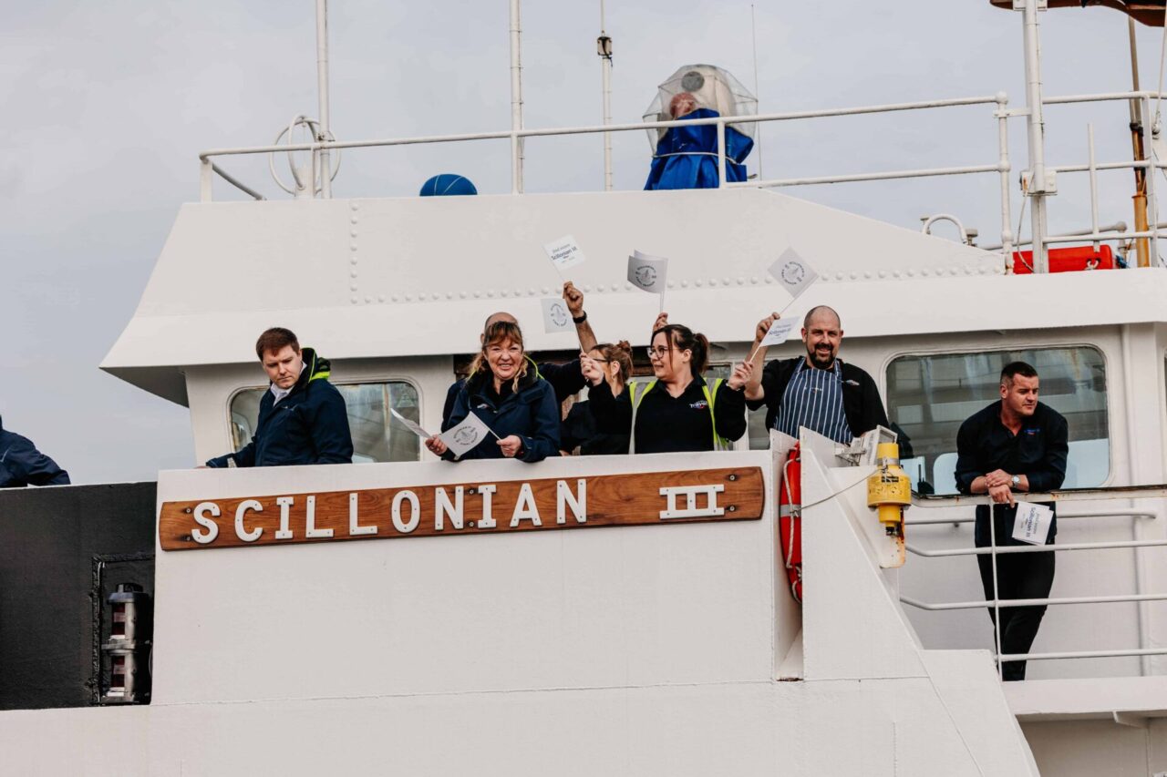 Scillonian III passenger crew waving flags on board.