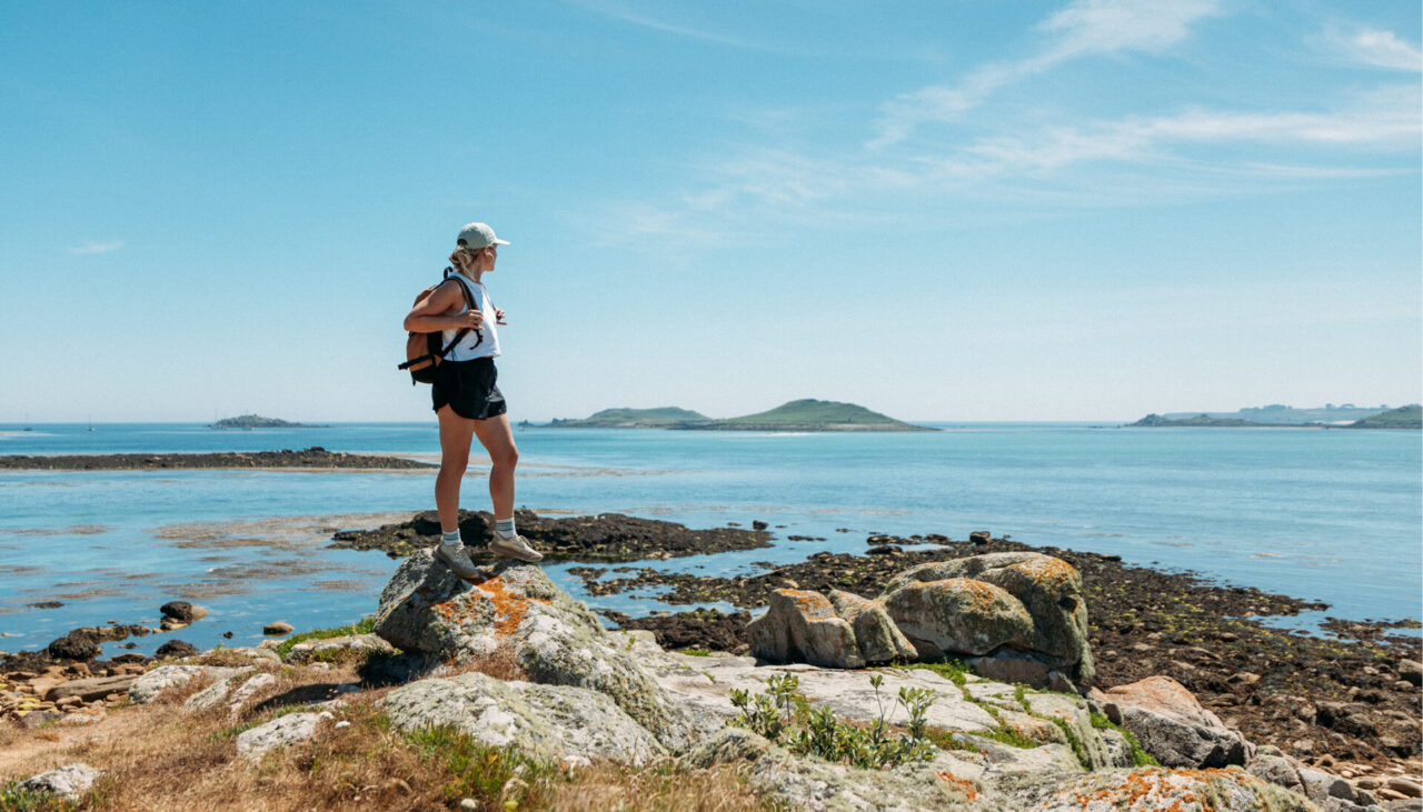 Isles of Scilly visitor stood on rocks overlooking islands on the horizon